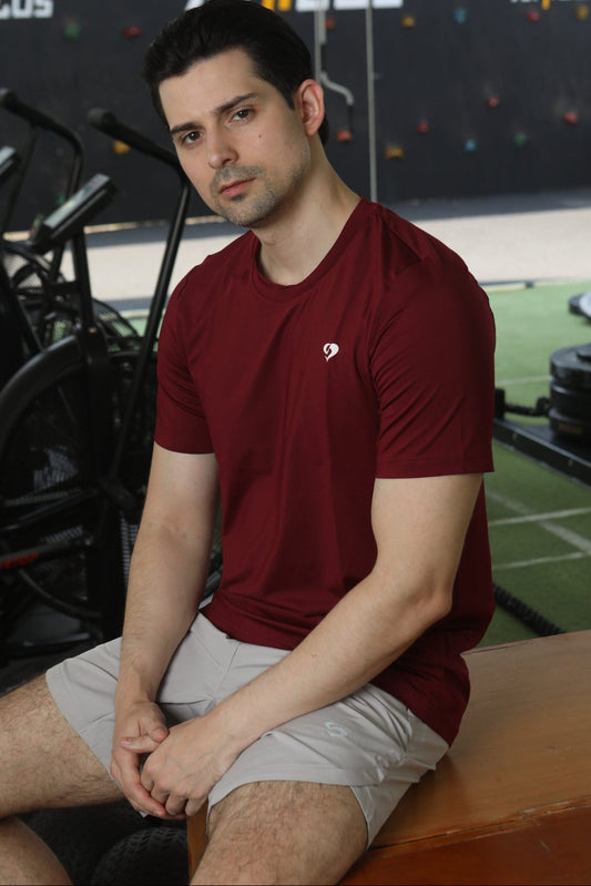 Man sitting on a bench in a gym in maroon everyday tshirt - Sandactive