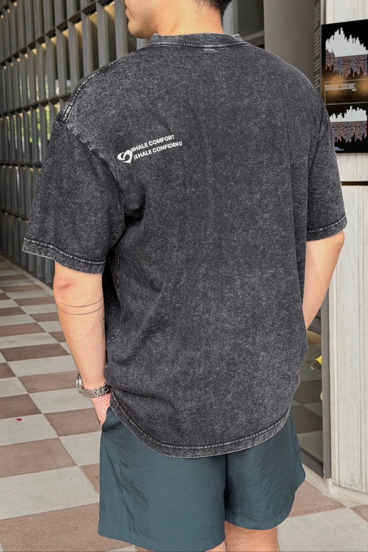 Person wearing a Vintage Oversized black t-shirt with a logo on the back, standing in an indoor setting.