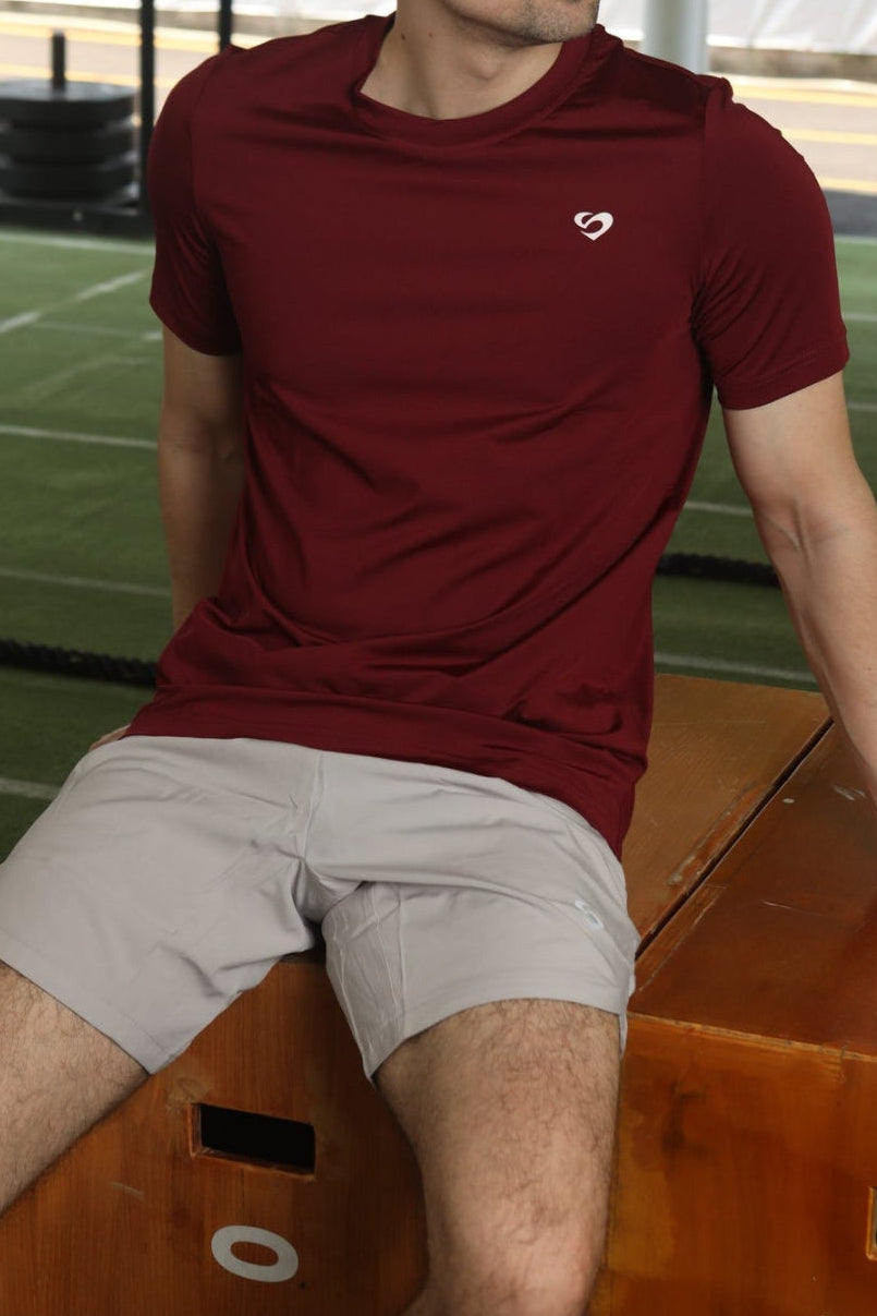 Man in maroon everyday tshirt and ivory white curved hem 8" shorts sitting on a wooden box - Sandactive