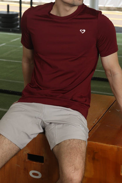 Man in maroon everyday tshirt and ivory white curved hem 8" shorts sitting on a wooden box - Sandactive