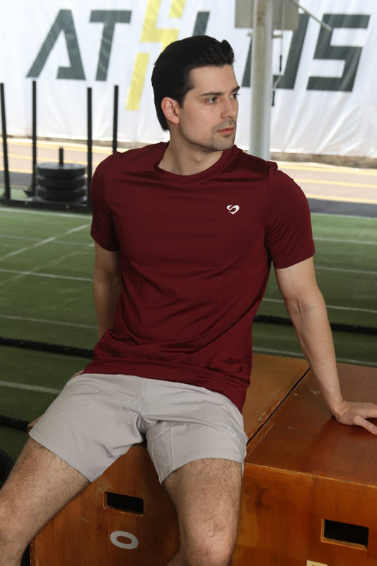Man in maroon everyday tshirt and ivory white curved hem 8" shorts sitting on a wooden box - Sandactive