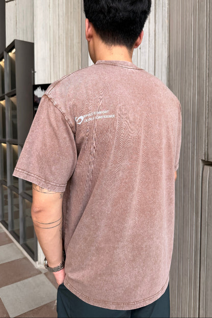 Person wearing a coffee tshirt with a logo at the back , standing on a rooftop with a cityscape background.
